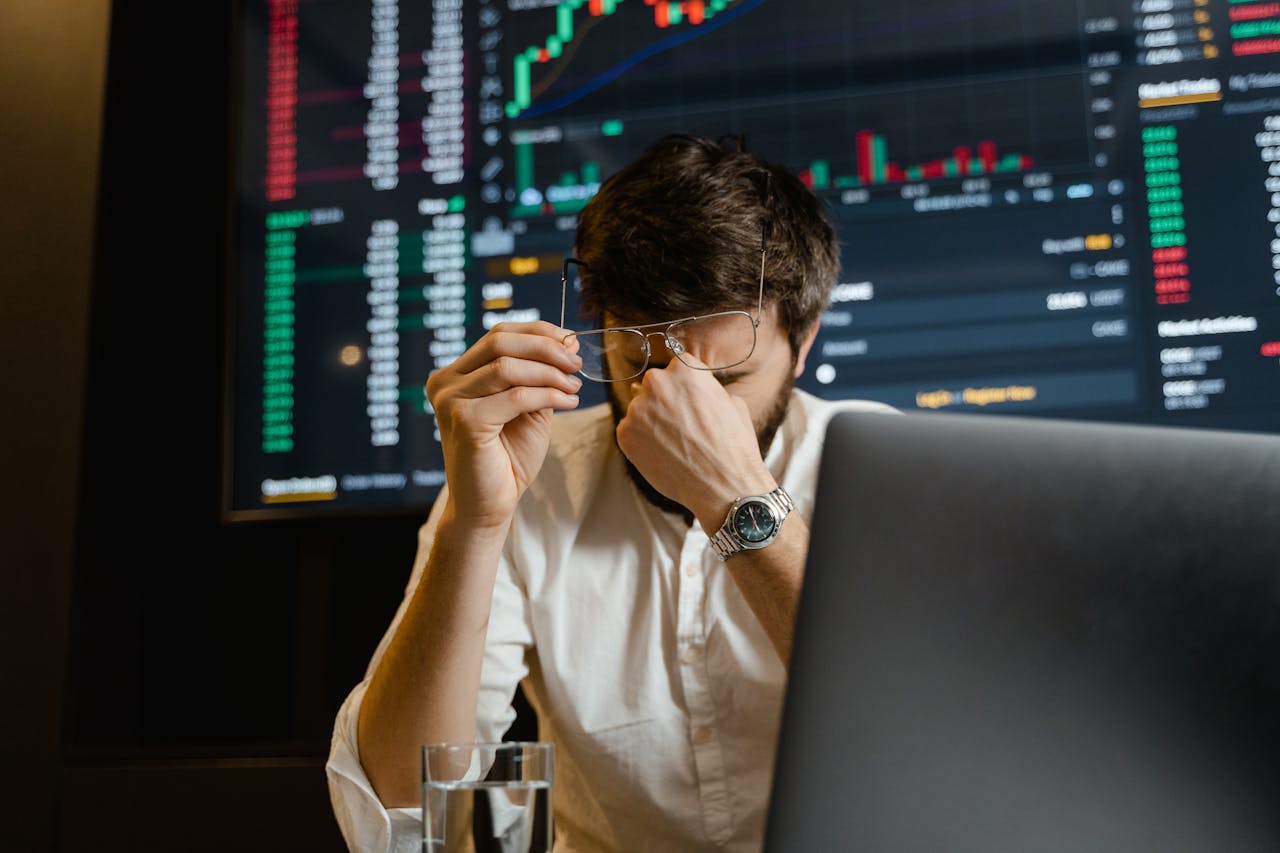 hero-img-01 A stressed man looks at stock market data on his computer screen in an office setting.
